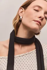 Bufanda angosta de tejido de punto fino, color negro, con diseño alargado y minimalista.