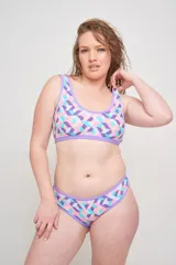 Conjunto de bikini estampado con motivos abstractos en tonos rosa, fucsia, verde y amarillo. El corpiño es de corte deportivo con breteles anchos y el calzón es de tiro alto con cintura elástica.