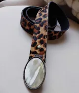 Cinto de cuero con estampado animal print y hebilla ovalada con aplique de nácar.