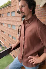 Camisa de manga larga blanca, confeccionada en lino, con cuello abotonado (button-down) y botones de color claro.