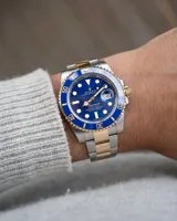Reloj Rolex Submariner réplica Triple AAA, con caja y brazalete de acero inoxidable, bisel azul y detalles dorados.