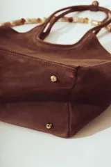Bolso tipo tote bag de gamuza color marrón oscuro, con asas de hombro largas y estructura rectangular.