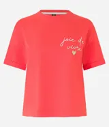 Remera roja de algodón con mangas cortas y cuello redondo. Presenta un bordado con la frase "joie de vivre" y un corazón de strass en el pecho.