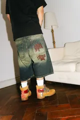 Bermuda baggy de jean con lavado verde, bordado en negro y rojo, cierre y botón personalizado, corte amplio y bolsillos grandes.