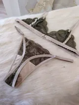 Conjunto de lencería de encaje verde musgo con detalles en beige, compuesto por un corpiño triangular sin aro y una tanga con tiras ajustables.
