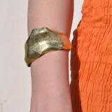 Brazalete rígido plateado con textura irregular.