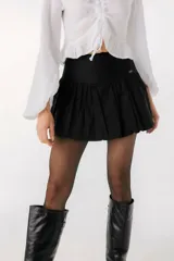 Minifalda negra con volados y detalle de etiqueta con logo en el lateral.