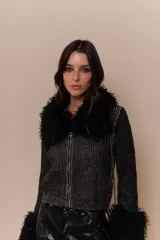 Saco negro con detalles de pelaje en cuello y mangas, ofreciendo un diseño elegante y moderno.