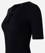 Blusa blanca de mangas cortas, confeccionada en Rib, con cuello redondo y lazos de terciopelo negros uniendo la abertura en la parte de abajo.