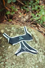 Conjunto de bikini negro con ribetes blancos, compuesto por un corpiño deportivo con logo y una bombacha clásica.