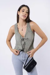 Chaleco corto sin mangas color verde salvia, confeccionado en tela perforada (broderie o calado). Presenta escote en V con lazos ajustables en el centro frontal.