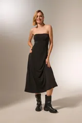 Vestido negro sin mangas, de corte ajustado al cuerpo y largo midi, con escote strapless.