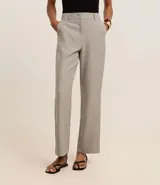 Pantalón de vestir gris claro, de corte recto, con bolsillos laterales y traseros. Se ajusta a la cintura con cinturón de cuero negro.