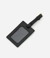 Bolso tipo valija grande color negro, con textura geométrica en relieve, cierre de cremallera, correa de mano, asa larga desmontable y tag de identificación.