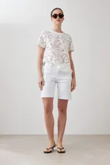 Blusa blanca de encaje con mangas cortas y cuello redondo.