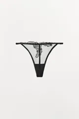 Tanga color dorado semitransparente con detalle de encaje floral en el frente. Cintura elástica fina y ajustable.