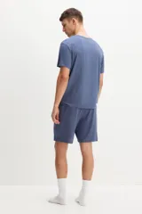 Conjunto de pijama azul de dos piezas en tejido de punto. Incluye una remera de manga corta con cuello redondo y un short con cintura elástica ajustable con cordón y bolsillos laterales.