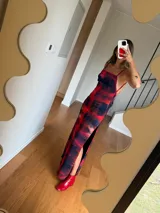 Vestido largo de tirantes finos con estampado abstracto en tonos rojo y negro, corte recto y aberturas laterales.