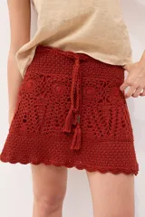 Minifalda tejida a crochet color ladrillo, con cintura alta y cordón trenzado con borlas.