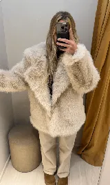 Campera de pelo sintético color beige, con cuello solapa, cierre con botones y bolsillos laterales.