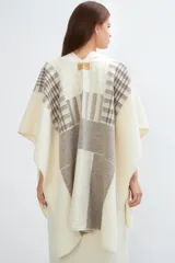 Ruana de lana fina color crudo con diseño de bloques en tonos de gris y beige. Terminación de crochet hecho a mano.