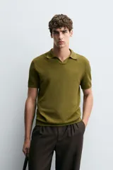 Jersey de punto color verde oliva, de calce relajado (relaxed fit), con cuello solapa y abertura frontal en forma de V. Es de manga corta y presenta acabados en rib en puños y ruedo.