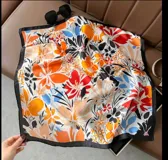 Pañuelo cuadrado de seda con estampado floral multicolor y borde negro.