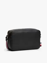 Cartera cruzada tipo cámara de poliuretano negro, con cierre principal de cremallera y monograma TH metálico dorado al frente. Incluye correa larga ajustable con cinta distintiva de rayas azul, blanco y rojo.