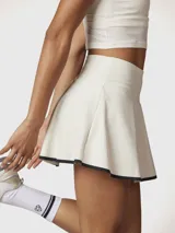 Falda skort blanca con borde negro en el dobladillo, confeccionada en tejido reciclado con tecnología Aircool. Incluye un short integrado con bolsillo.