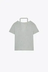 Camiseta color beige de tejido de punto, con cuello halter y escote pico. Tiene cierre frontal con botones y mangas cortas.