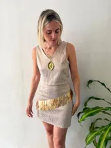 Falda corta de brocado color beige con estampado floral en gris claro y aplique de flecos dorados en diagonal.