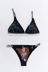 Conjunto de bikini negro con estampado de palmeras en el corpiño y tigres en la bombacha. El corpiño es de corte triangular con tirantes finos y la bombacha es de corte clásico.