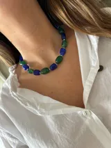 Collar corto tipo gargantilla compuesto por cuentas facetadas de vidrio o piedra en tonos azul lapislázuli y verde esmeralda, intercaladas con pequeñas cuentas espaciadoras plateadas.
