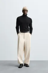 Pantalón negro de corte amplio, tipo balloon fit, con pinzas en la cintura, bolsillos laterales y traseros de ojal.