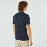 Remera polo azul marino de piqué de algodón con estampado de pequeños detalles geométricos en blanco y rojo.