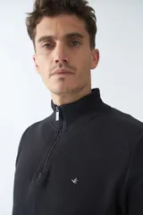 Buzo negro de algodón con cuello alto y medio cierre. Tiene logo bordado en el pecho y puños en las mangas.