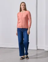 Cardigan tejido en hilado fino, color rosado, con escote redondo y cierre frontal con botones.