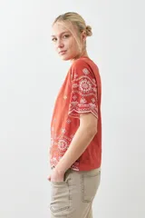 Remera color ladrillo con bordado de flores blancas en el ruedo y las mangas.