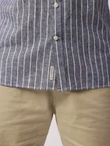 Camisa de manga larga a rayas verticales azules y blancas, con cuello abotonado y bolsillo en el pecho. Confeccionada en lino y algodón.