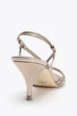 Sandalia de tacón fino color dorado, con tiras finas anudadas en el empeine y tira trasera.