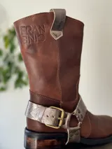 Bota de cuero marrón con estribo desmontable plateado.