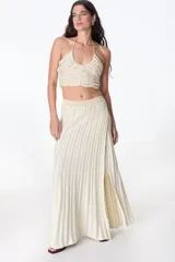 Falda larga color crema con lurex dorado, de tejido de punto acanalado y corte recto con abertura lateral.