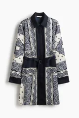 Vestido camisero de manga larga, con cuello camisero y cierre frontal de botones ocultos. Presenta un estampado tipo pañuelo en tonos blanco, azul marino y azul claro, y se ajusta a la cintura con un cinturón extraíble con argollas metálicas.
