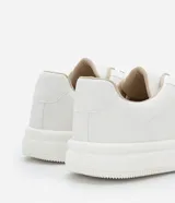 Championes blancos de cuero sintético con cordones y suela gruesa.
