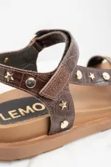 Sandalias marrones de cuero con suela gruesa y tachas doradas en forma de estrella y circulares.