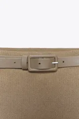 Falda midi color beige de punto con cinturón a contraste con hebilla metálica.