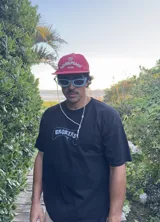 Gorra de béisbol color rojo vino con visera curva. Estampado frontal con un corazón y el texto "LOVE & PEACE" en blanco, y debajo "PP-ONE".