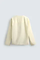 Camisa color crema de corte amplio, confeccionada en popelín de algodón. Tiene cuello redondo y mangas largas.