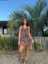 Vestido corto con estampado abstracto en tonos rosados, escote en V y breteles finos que se atan al cuello. Tiene corte en la cadera y falda con ruedo irregular y pico en lateral.