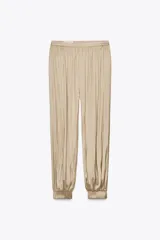 Pantalón bombacho color beige de tiro alto, con elástico en la cintura y en los tobillos.